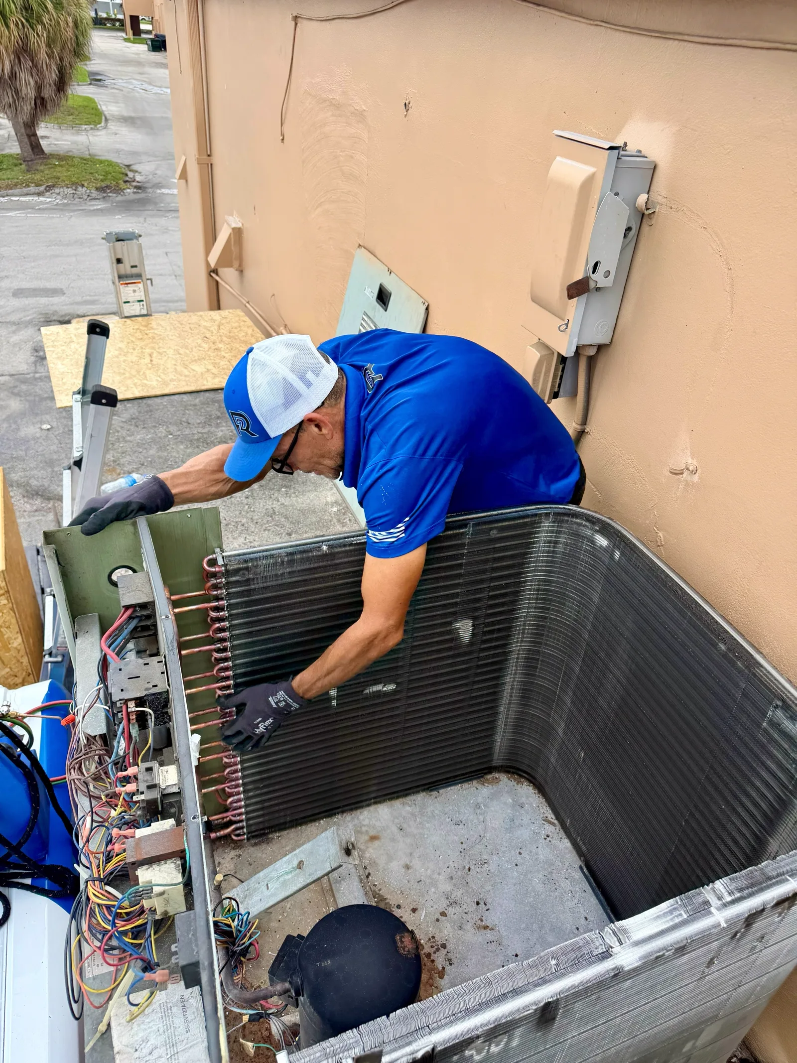 2R Cooling technician fitting the replacement OEM condenser coil into a Trane commercial split-system condensing unit in Fort Pierce, Florida