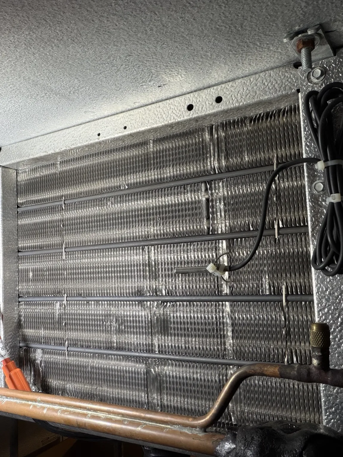 Walk-in freezer evaporator coil fins and defrost elements visible after ice was cleared