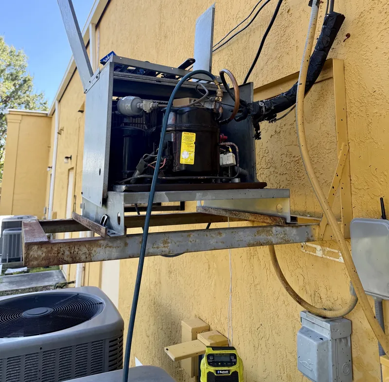 Wider view of the replacement compressor installed in the Francesca's Pizza walk-in cooler condensing unit, with a service hose attached
