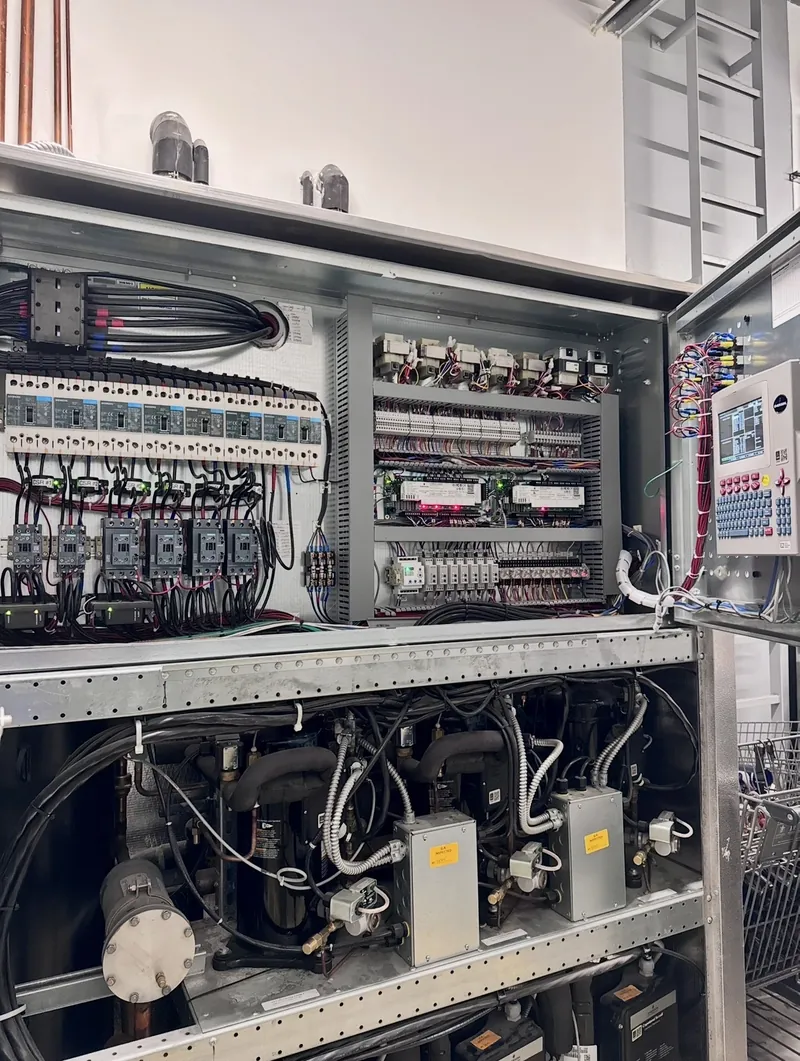 Supermarket refrigeration rack in Port St. Lucie with its electrical control panel open above the compressors