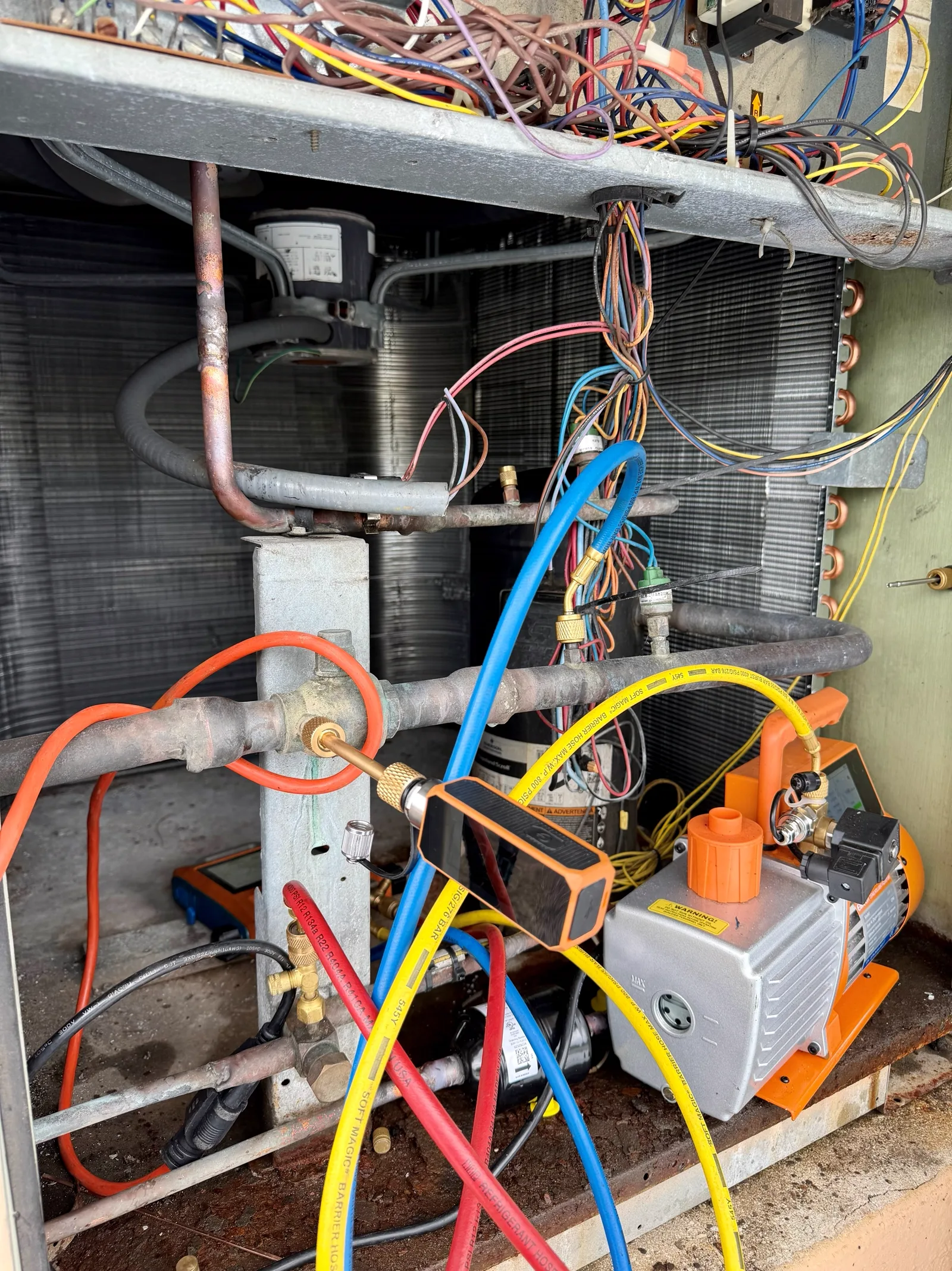 Vacuum pump, micron gauge and manifold hoses connected to the Trane condensing unit during evacuation before the R-410A charge