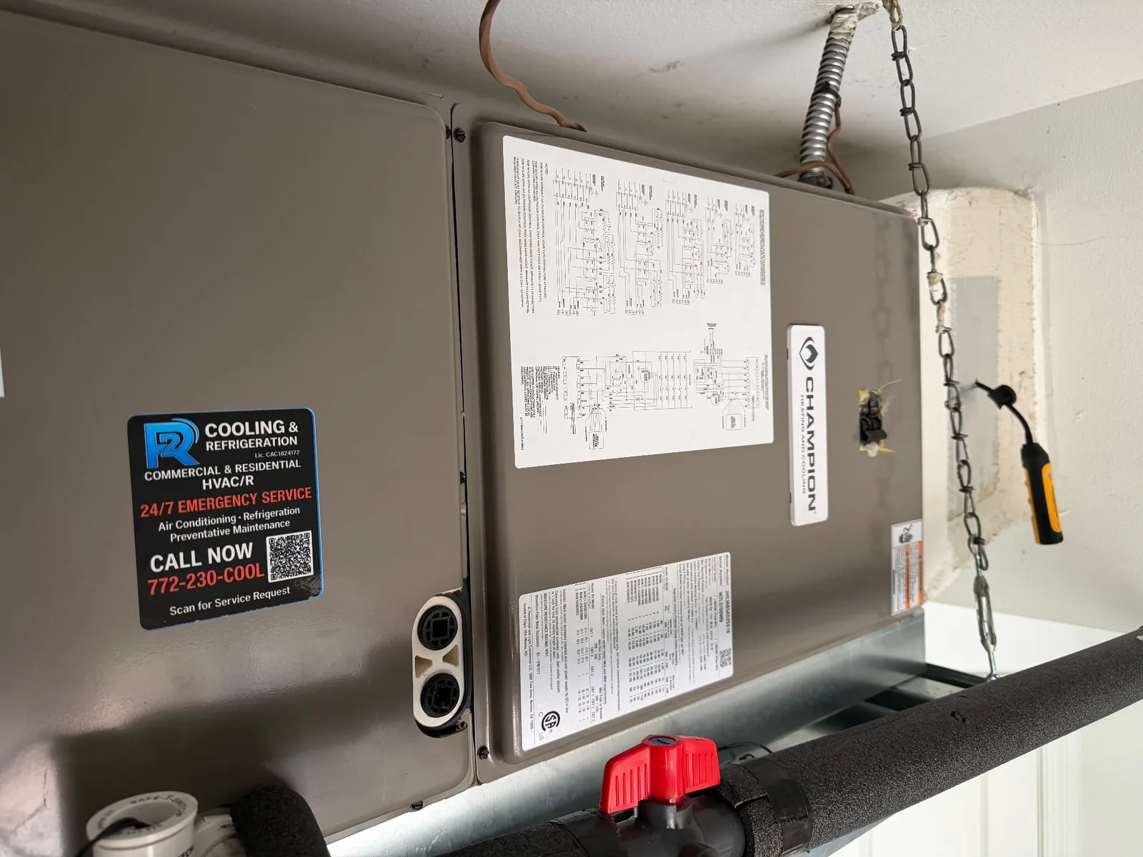 Champion air handler suspended in a Port St. Lucie garage with insulated line set, condensate piping and the 2R Cooling service label