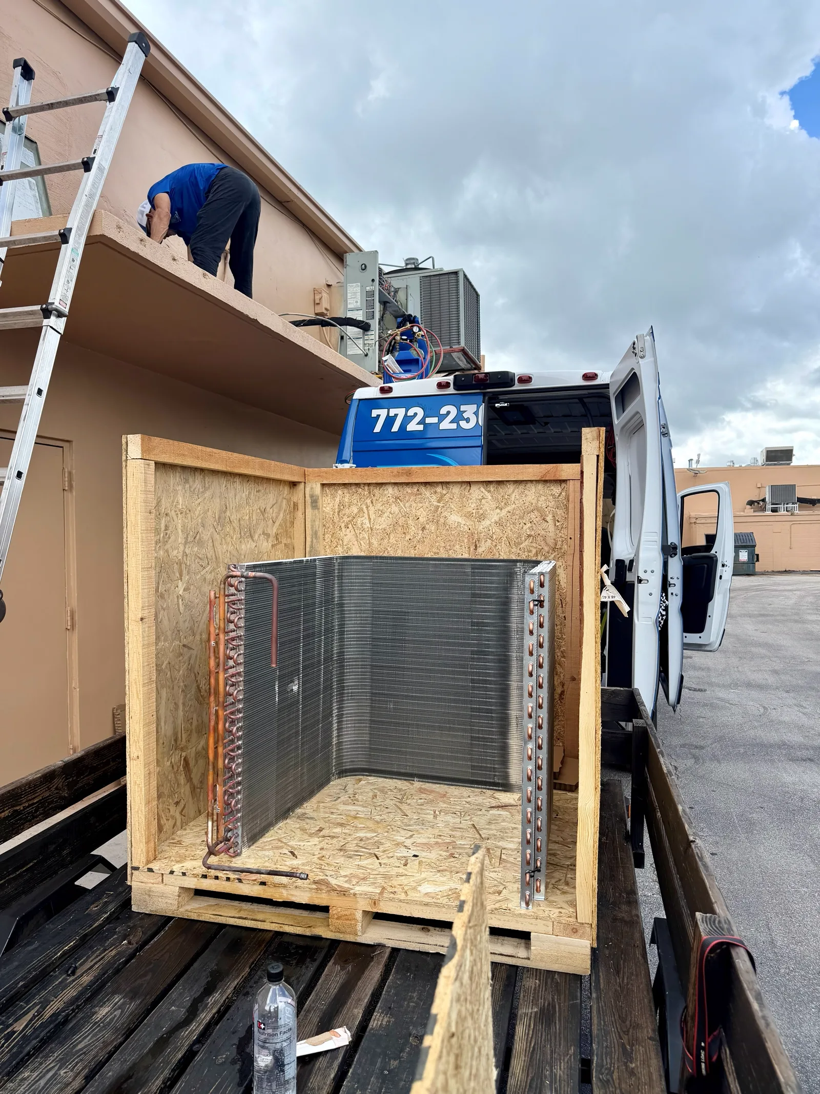 New OEM Trane condenser coil, part COL16052, in its shipping crate on the service truck before installation