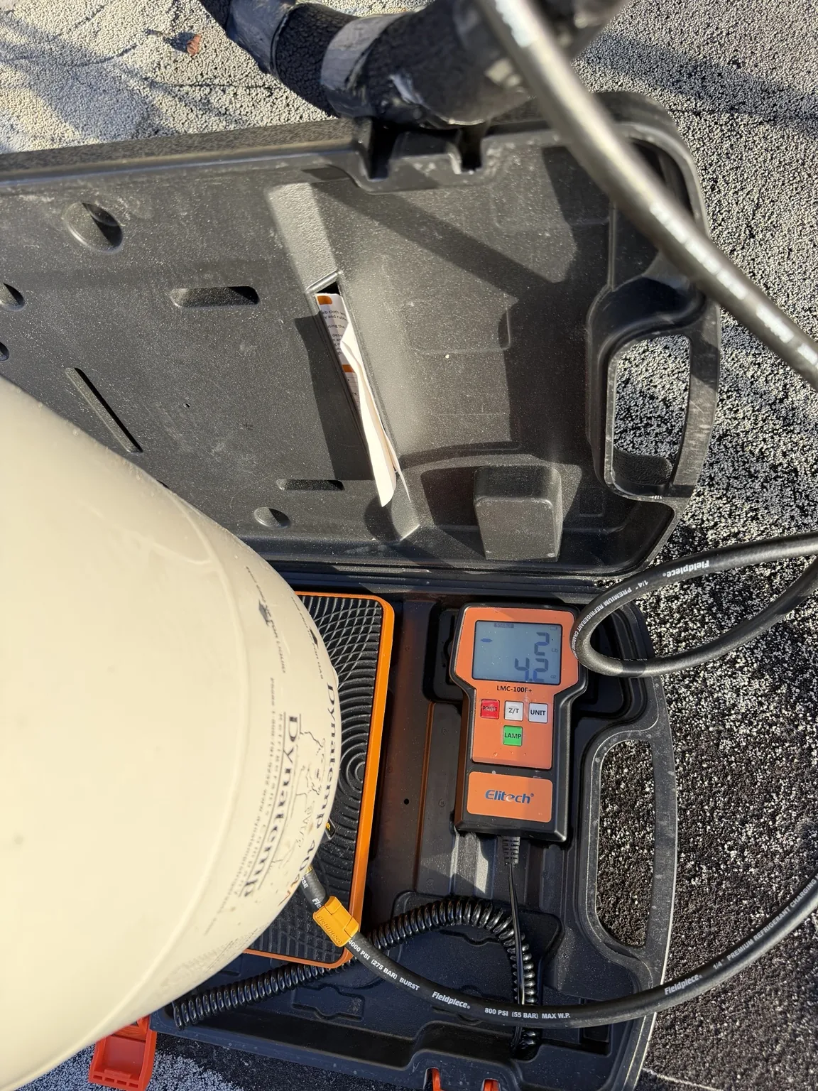 Refrigerant cylinder on a digital charging scale beside the manifold hoses during walk-in freezer service in West Palm Beach
