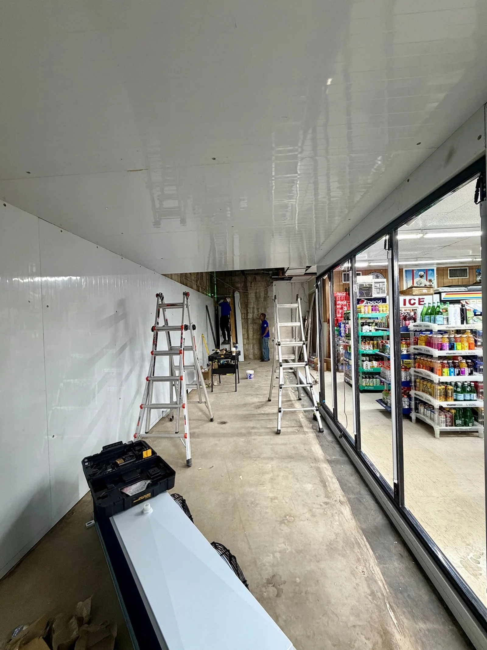 Walk-in cooler ceiling panels and glass-door frontage during assembly