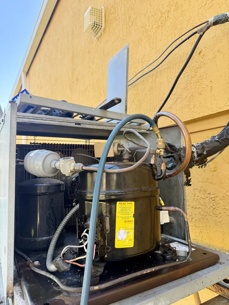 Replacement Tecumseh compressor installed in the existing walk-in cooler condensing unit at Francesca's Pizza in Port St. Lucie, with a service hose attached