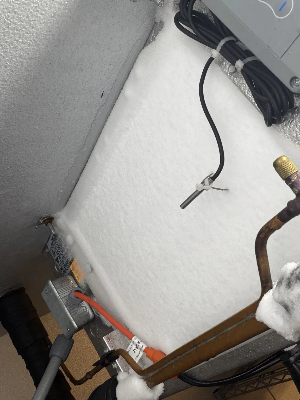Heavy frost and ice obscuring the evaporator coil inside a commercial walk-in freezer
