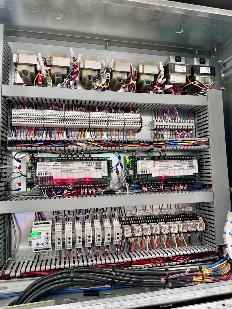 Close-up of the rack electrical control panel showing two Emerson controller boards, terminal blocks and relays