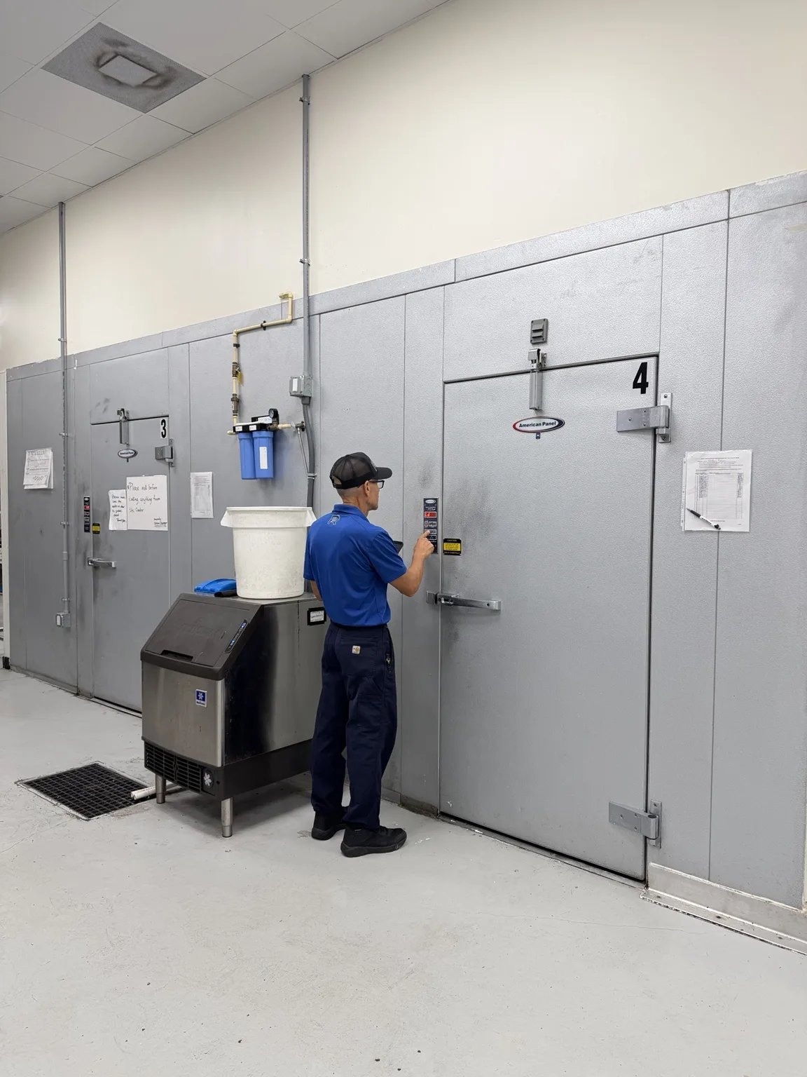 2R Cooling technician working at the exterior controls of a commercial walk-in freezer in Boynton Beach, Florida